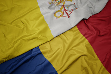 waving colorful flag of romania and national flag of vatican city.