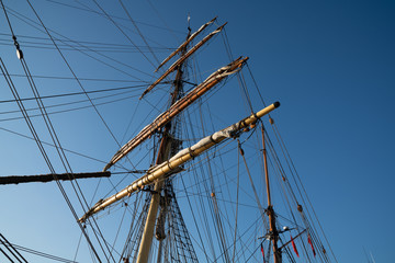 Masts, spars and rigging from low point of view against blue sky.