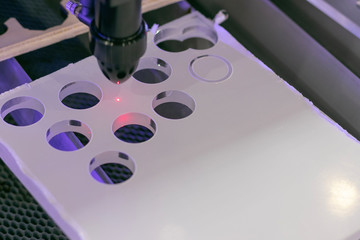 Details of an industrial CNC laser cutting machine. Drilling holes in plexiglass panel with a hot...