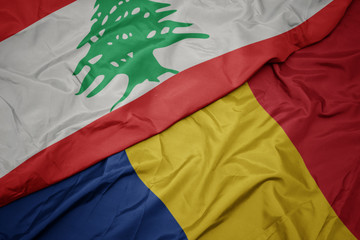 waving colorful flag of romania and national flag of lebanon.