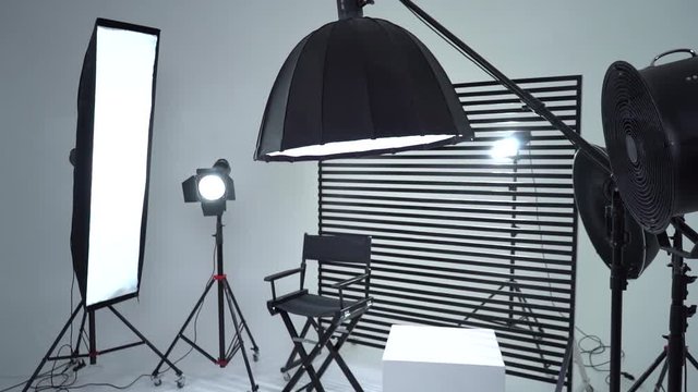Crystal White room cyclorama. Modern photo studio with professional equipment. Empty photo studio with lighting equipment. Interior of modern photo studio with director production chair.