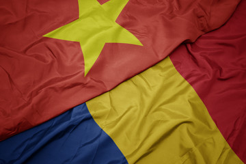 waving colorful flag of romania and national flag of vietnam.