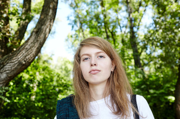Obraz premium Beautiful attractive woman in white t-shirt posing in the summer park. Active smiling girl resting outdoors