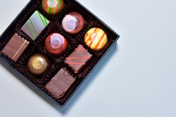 Set of delicious chocolate candy in black elegant box with selective focus on neutral background....