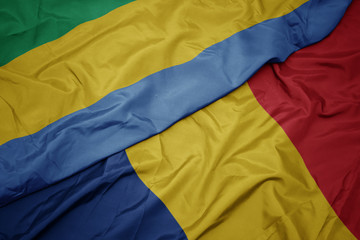 waving colorful flag of romania and national flag of gabon.