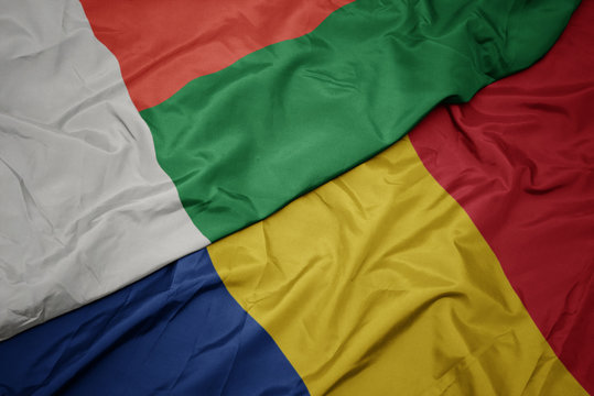 waving colorful flag of romania and national flag of madagascar.
