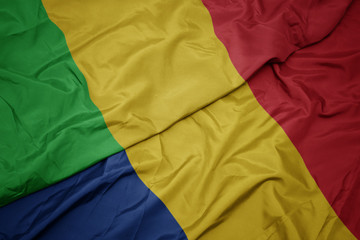 waving colorful flag of romania and national flag of mali.