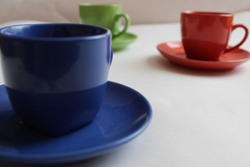 Cup mug with saucer close up in the background red and green mugs on a white background