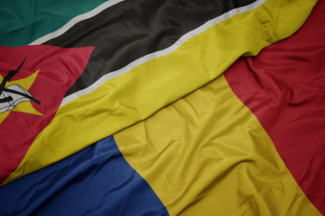 waving colorful flag of romania and national flag of mozambique.