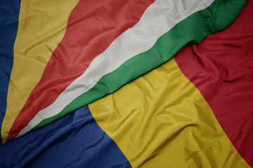 waving colorful flag of romania and national flag of seychelles.