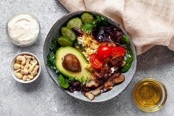 Keto dish with eggs, tomato, avocado, bacon, cashew nuts, chia seeds, olive oil and cream. Healthy fats concept. Top view