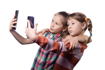 Two cute little girls posing with mobile phones.