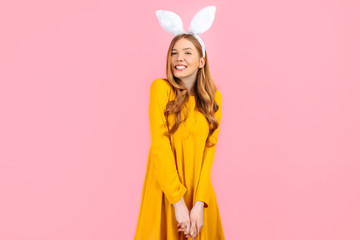 Holiday season of rabbit and eggs. Happy woman in Easter Bunny ears isolated on pink background.