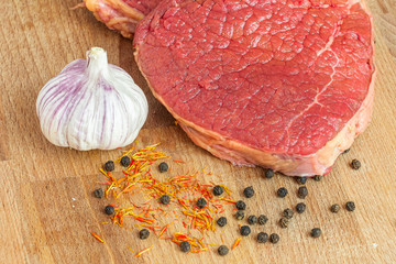 Closeup fresh red meat, garlic, species for cooking.