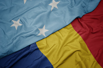 waving colorful flag of romania and national flag of Federated States of Micronesia .