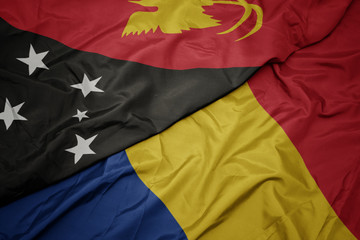 waving colorful flag of romania and national flag of Papua New Guinea .