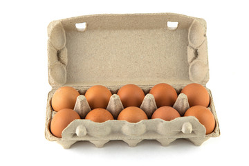 One dozen chicken eggs in a cardboard container on a white background