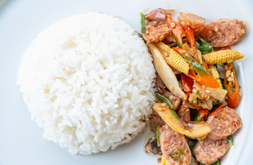 Asian spicy hot food or Thai food, closeup top view above Thai sour pork or Nham fried with chili and mix vegetable with white cooked rice on round white plate background for cooking delicious meals
