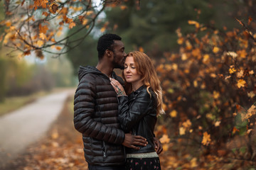 Happy Interracial couple posing in blurry autumn park background