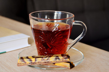 glass cup with tea and chocolate on the table with a book coziin in the house