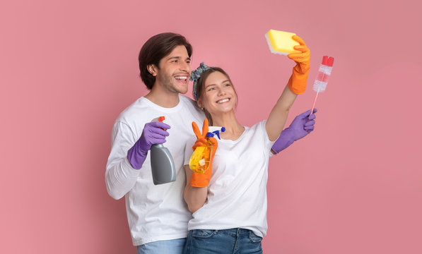 Cleaning Fun. Cheerful millennial couple taking selfie, using sponge like smartphone