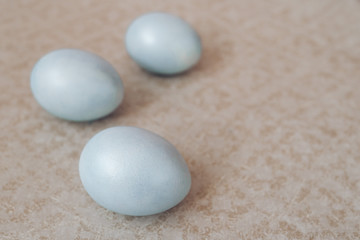 Fototapeta na wymiar blue pearl easter eggs on a beige background, pastel colors