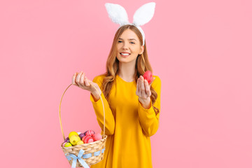 Happy Easter. happy young woman wears rabbit ears on Easter day and holds a basket of Easter eggs, on an isolated pink background