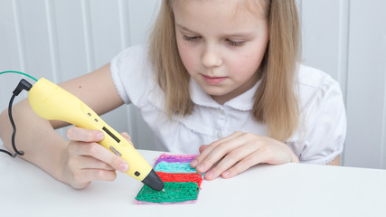 The girl is engaged with a 3D pen. Light background. Selective focus. Classes at home.