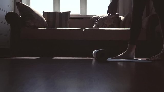 A young girl is arranging a yoga mat at home. Quarantine. Slow motion.