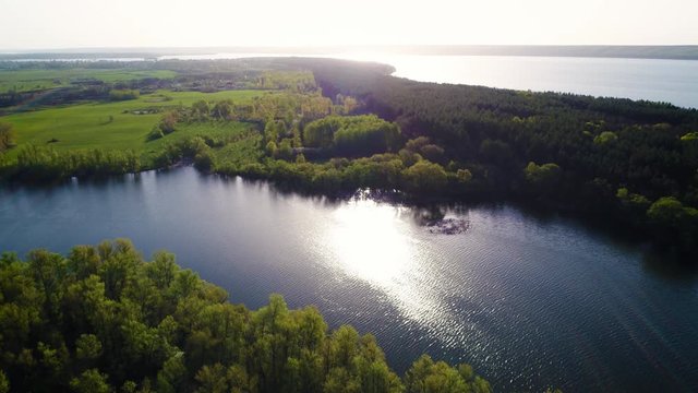 Aerial: Flying over a lake with sun illuminating the water.