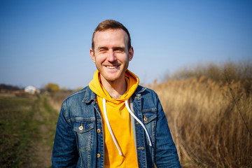 Smiling man enjoying wind blowing in forest. Happy man feeling joy while walking at nature, free space on green trees background. Life love, joy, fresh air, renovation concept