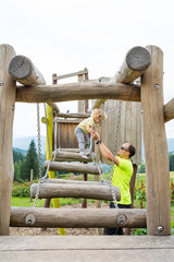 Father and daughter playing and climbing at outdoor playground.