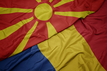 waving colorful flag of romania and national flag of macedonia.