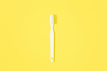 Toothbrush on yellow pastel background.