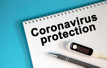 Obraz premium CORONAVIRUS PROTECTION - text on a notepad. Lie a pen and a medical thermometer