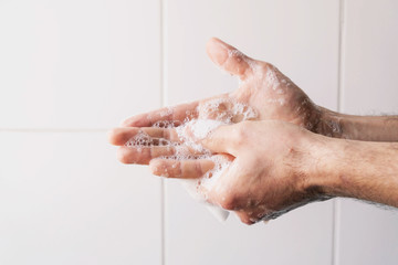 Man cleaning his hands using liquid disinfectant soap and water in bathroom.