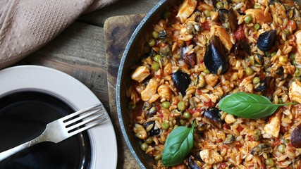 paella from orzo pasta with mussels, seashells and chicken. Seafood paella, traditional spanish dish. Paella on rustic black wooden table. Top view
