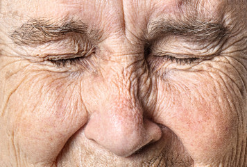 Wrinkled old face close up. Portrait of an old woman with closed eyes.
