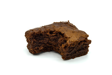 A close up of a chocolate brownie cake with a bit taken out isolated on a white background