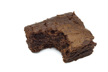 A close up of a chocolate brownie cake with a bit taken out isolated on a white background