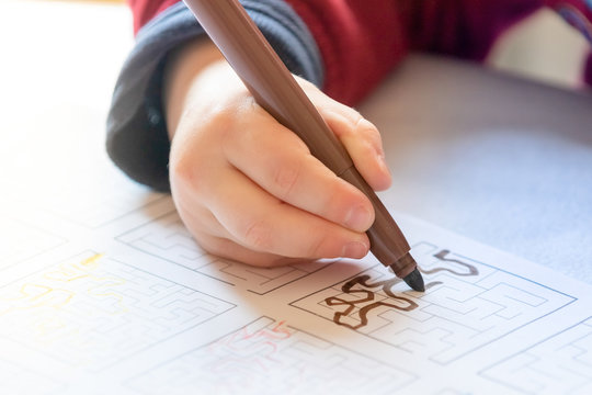 Young kid drawing a maze and playing board game