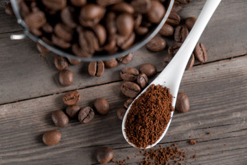 Arabica coffee beans in a small miniature bucket. ground coffee in a white ceramic spoon on a wooden background.