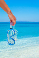 Girl holding a scuba mask by the sea