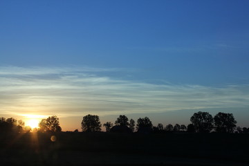 Fototapeta na wymiar Sunset with a flare on the horizon under the blue sky