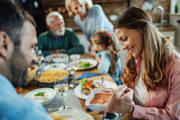 Young happy couple enjoying in lunch with their family in dining room.