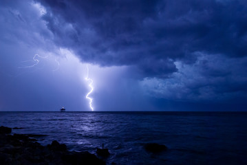 A storm front with rain and curved lightning striking the sea near an abandoned marine science...