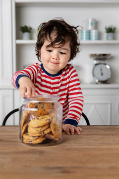 Cute toddler grabbing a cookie from cookie jar