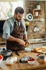 Young man peeling avocado while preparing food in the kitchen.