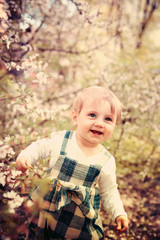 Portrait of    baby near blooming spring trees.