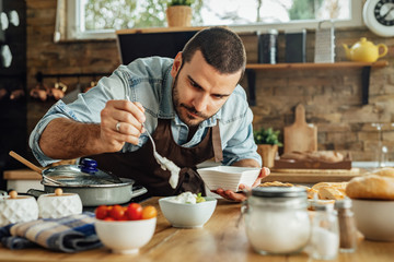 Young man making dipping sauce while preparing food in the kitchen.